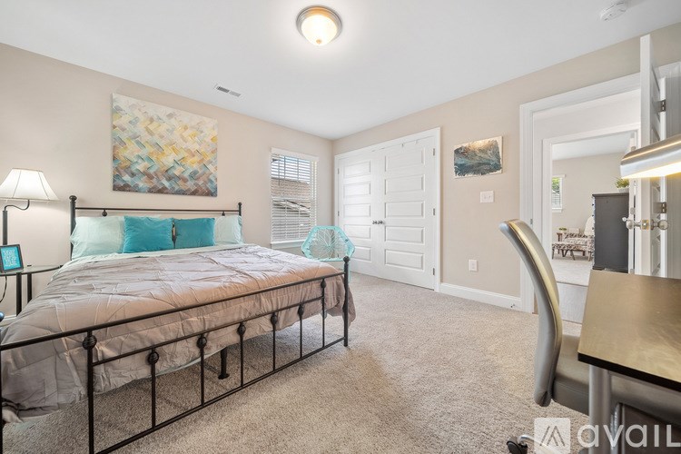 A bedroom with a bed, chair, and a painting on the wall.