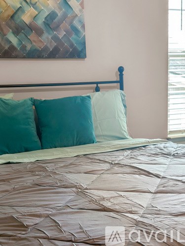 A bed with a blue headboard and two blue pillows.