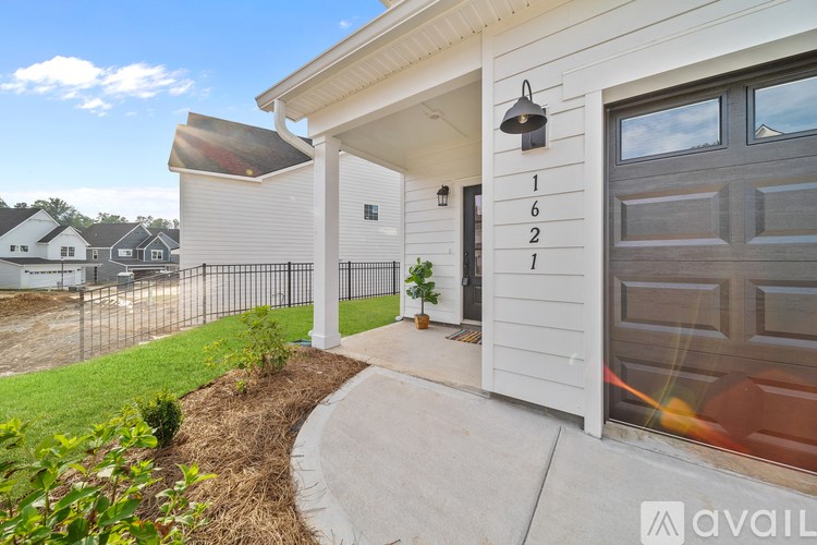 A white house with a black gate and a small garden in front.