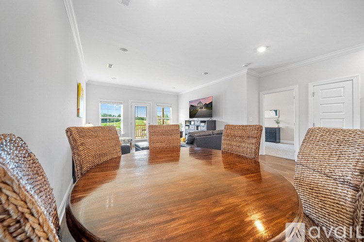 A wooden table surrounded by wicker chairs in a room with a window.