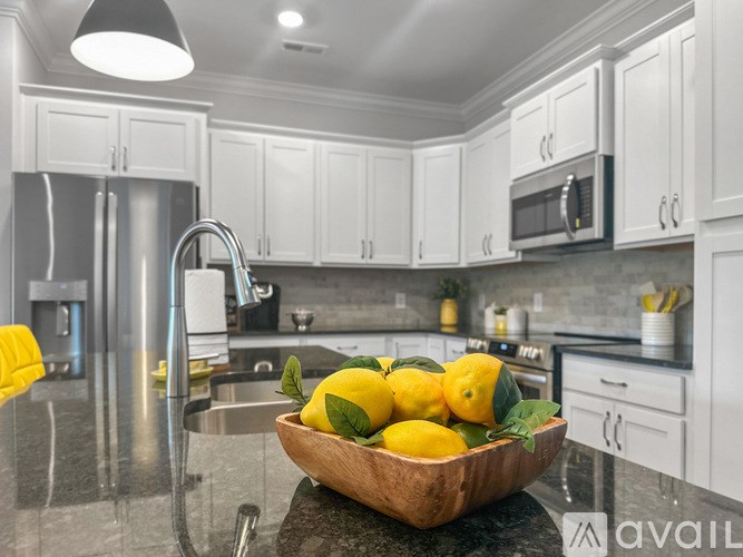 A kitchen with white cabinets and a bowl of lemons on the counter.