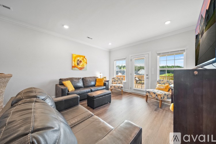 A living room with a leather couch and a painting on the wall.