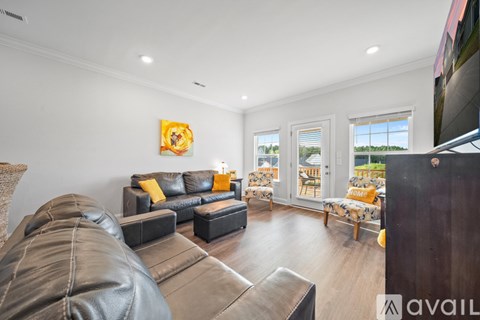 A living room with a leather couch and a painting on the wall.