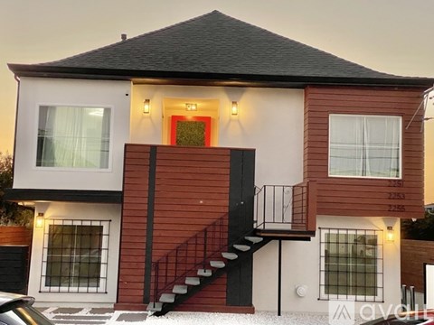 A modern two-story house with a red and white exterior and a black roof.