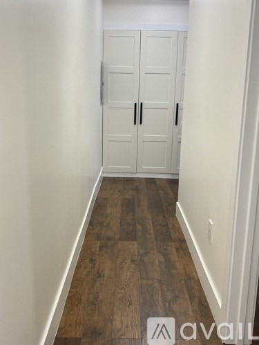 A hallway with a white door and wooden flooring.