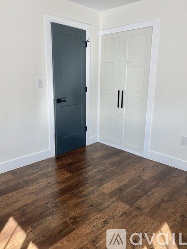 A room with a dark grey door and a white door with a glass panel.