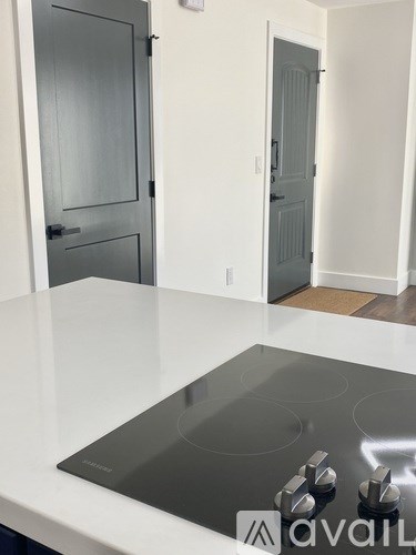 A kitchen with a white counter top and a black stove top.