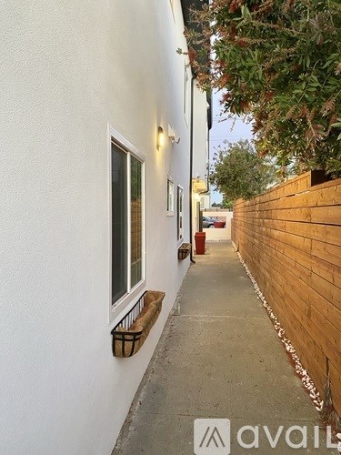 A narrow alley with a wooden fence on one side and a white building on the other.