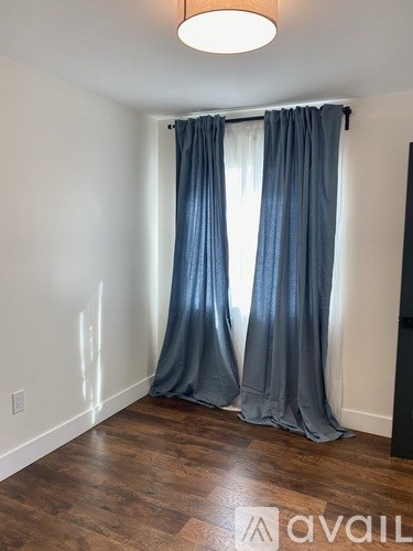 A room with a window covered by blue curtains.