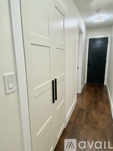 A hallway with white doors and a black door at the end.