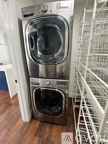 A stack of two front loading washing machines in a laundry room.