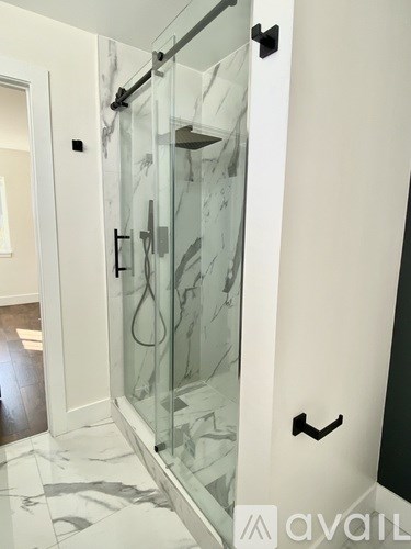 A glass shower door in a bathroom with a marble floor.