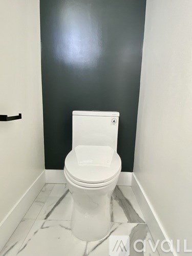 A white toilet in a bathroom with a grey wall.