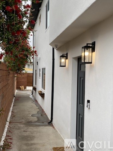 A narrow alley with a black door and wall lights.