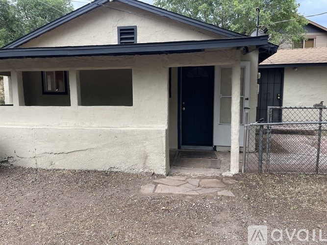 A small house with a black door and a black gate.