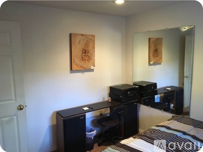 A room with a bed, desk, and two computer towers.