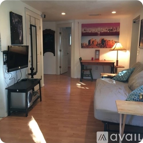 A living room with a couch, a television, and a painting on the wall.