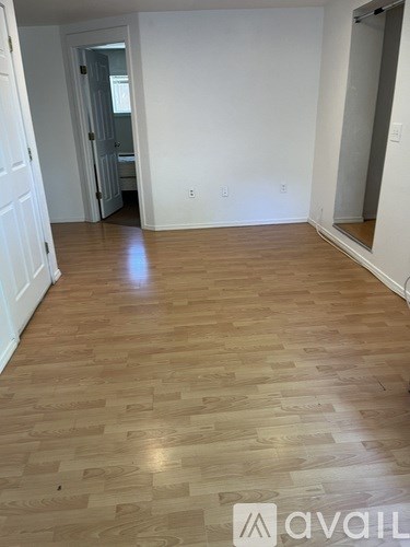 A room with wooden flooring and white walls.