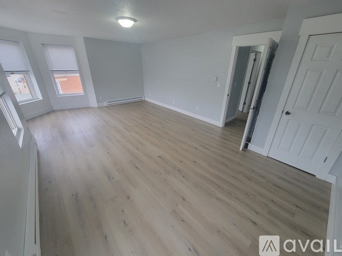 A spacious room with wooden flooring and white walls.