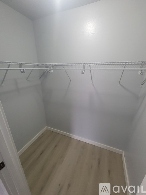 A white closet with a wooden floor and a white door.