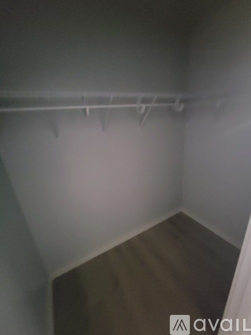 A small, empty room with a wooden floor and white walls.