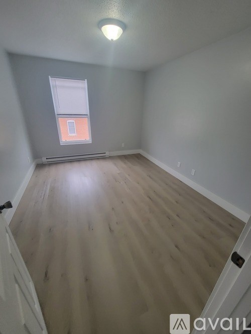 A room with wooden flooring and a window with a white frame.