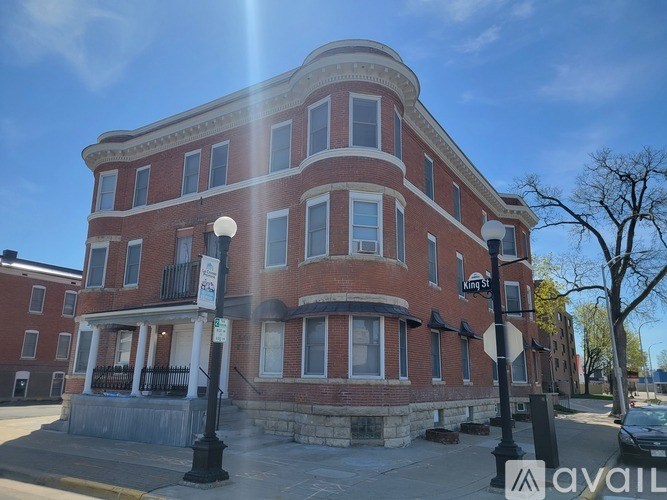 A red brick building with a curved top floor and a balcony on the second floor.