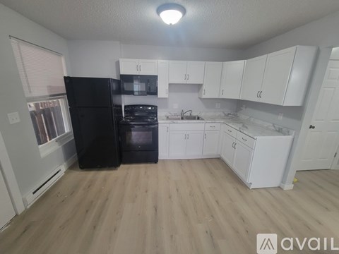 A kitchen with black appliances and white cabinets.