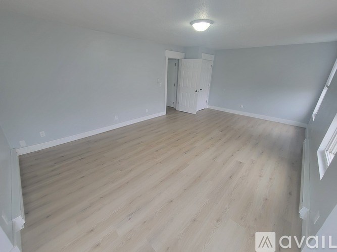 A spacious room with wooden flooring and a white door.