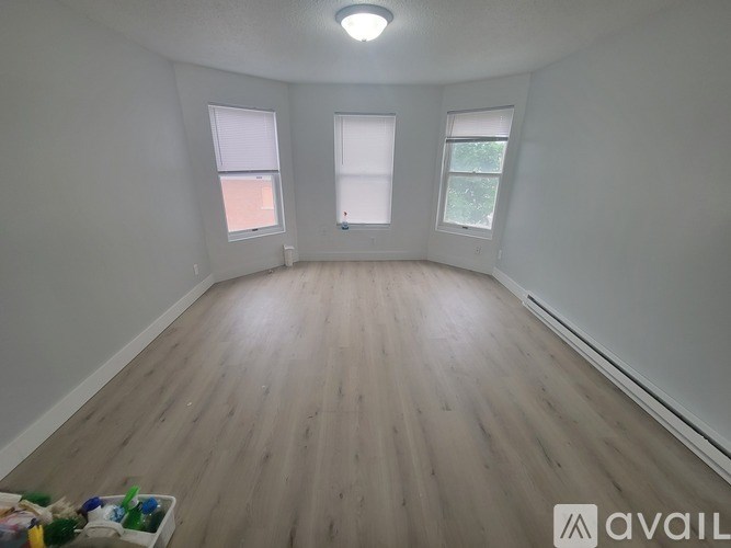 A room with wooden flooring and two windows.