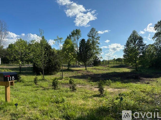 A field with a mailbox labeled 118 and trees in the background.