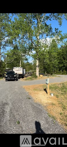 A black vehicle is parked on a gravel road.