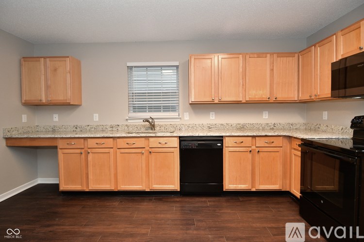 A kitchen with wooden cabinets and a black dishwasher.