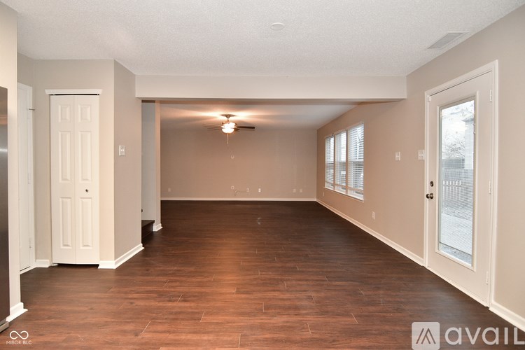 A spacious room with wooden floors and white walls.