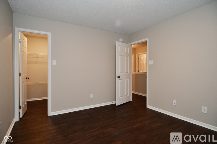 A room with two open doors and wooden floors.