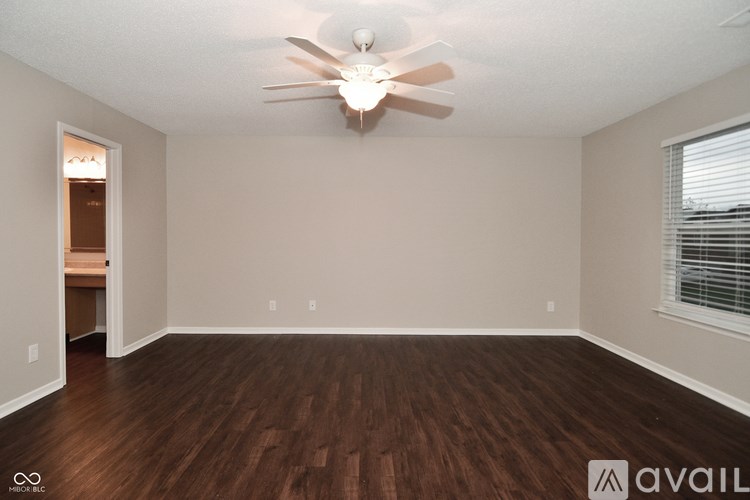 A room with a ceiling fan and wooden flooring.