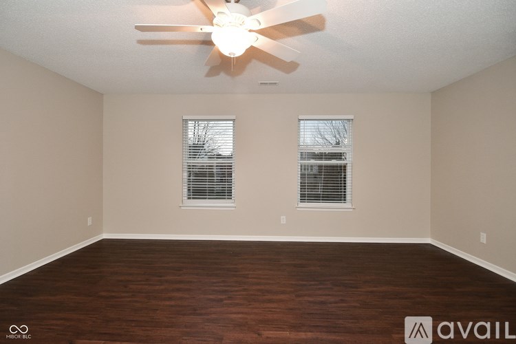 A room with a ceiling fan and two windows.