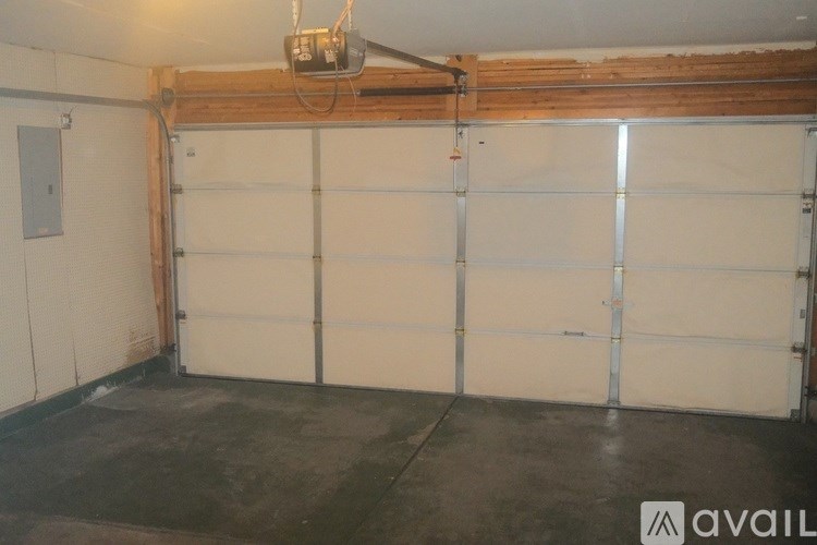 A large garage with a white door and a wooden beam on the ceiling.