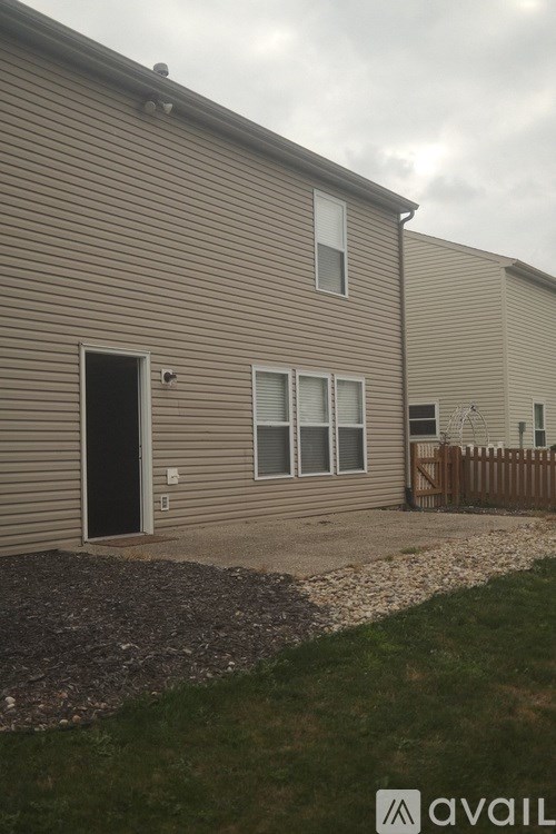 A beige house with a black door and a brown fence.