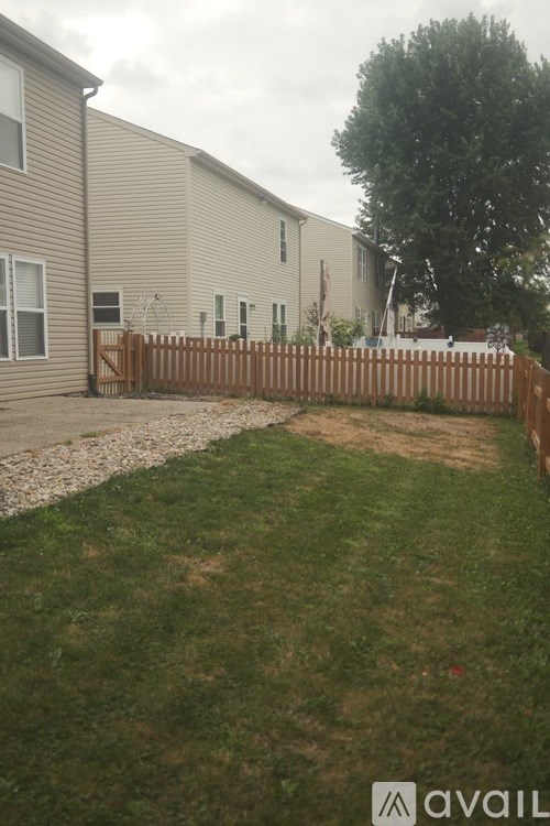 A grassy area in front of a building with a wooden fence.