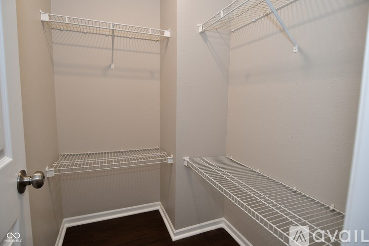 A walk in closet with two shelves and a door.