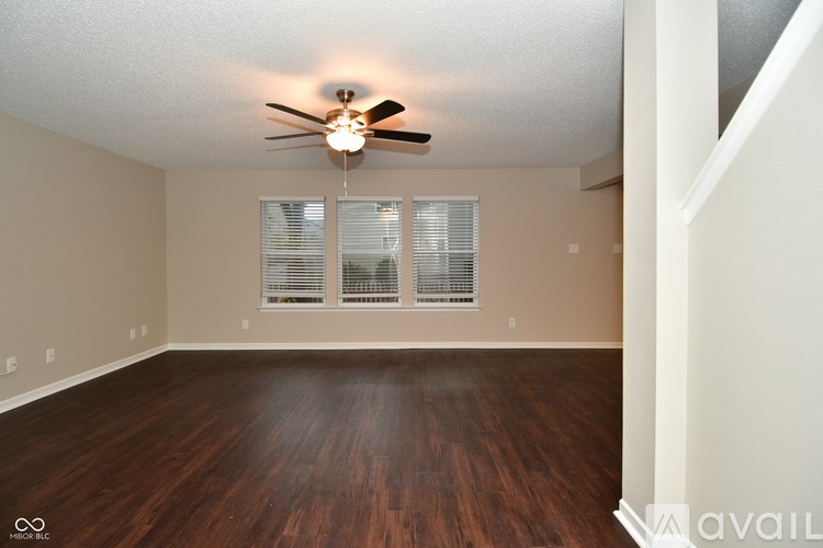 A room with a ceiling fan and wooden flooring.