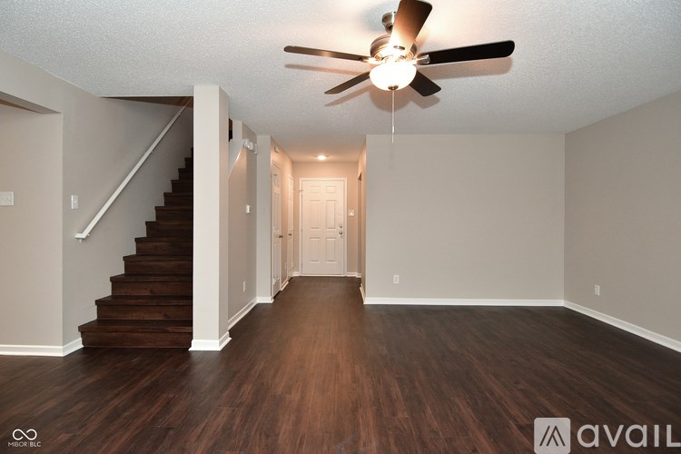 A spacious room with a staircase and a ceiling fan.