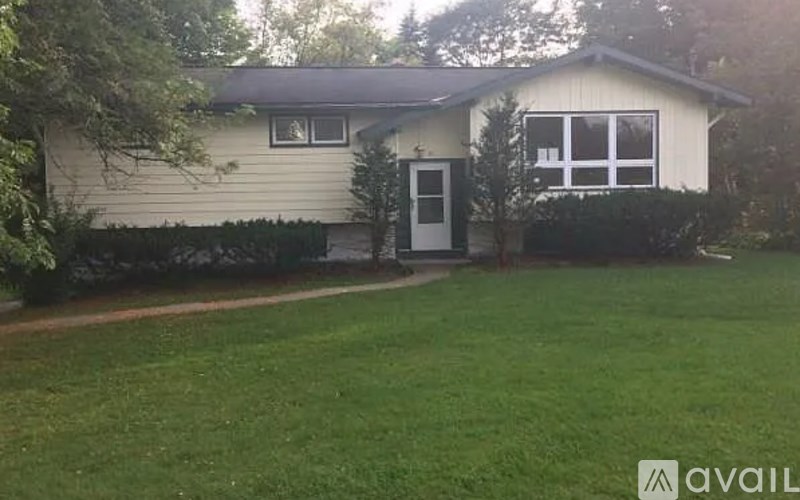 A house with a white door and windows is surrounded by a green lawn.