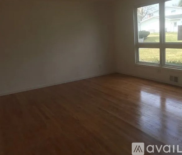 A room with wooden flooring and a large window.