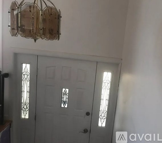 A white door with a glass panel and a chandelier hanging from the ceiling.
