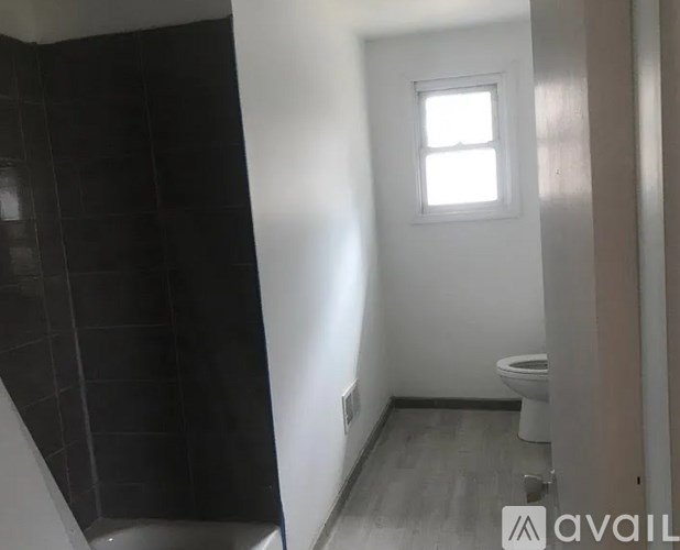 A bathroom with a toilet, a window, and a tiled shower area.