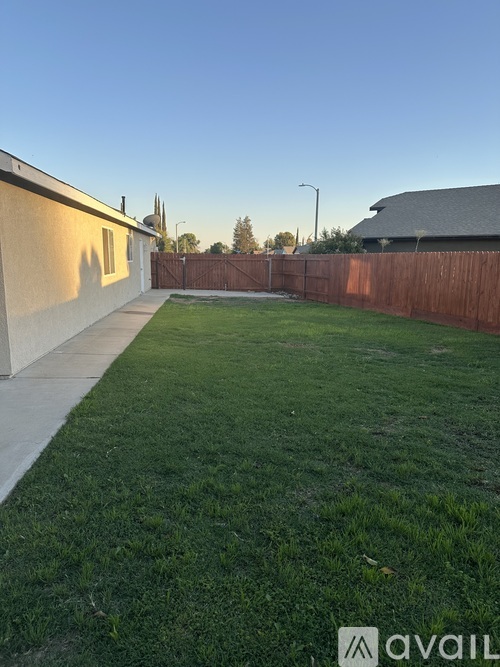 A backyard with a wooden fence and a house.