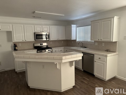 A kitchen with white cabinets and a white island.