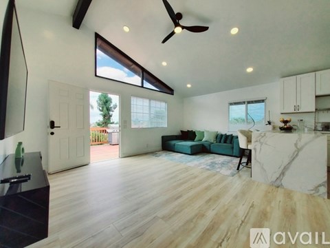 A spacious living room with a dark wood floor and white walls.